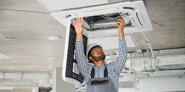 Technician working on a ceiling-mounted air conditioning unit