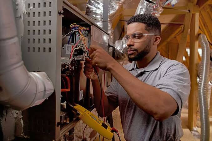 Heating technician inspecting furnace wiring