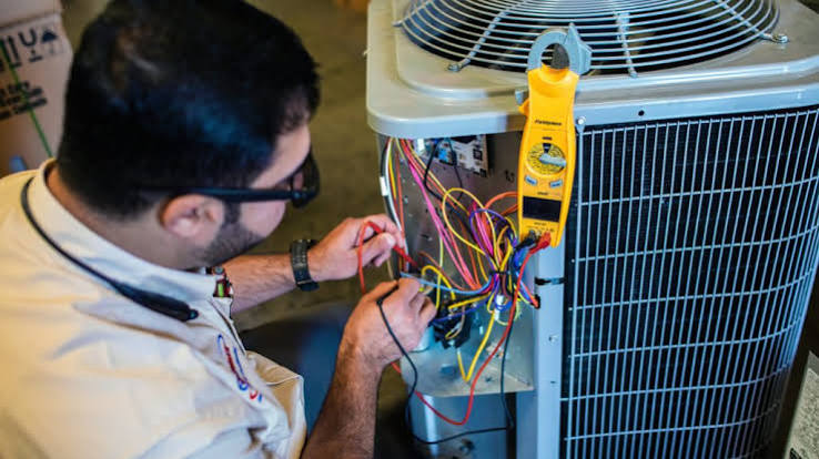 Technician testing the electrical components of an air conditioning condenser