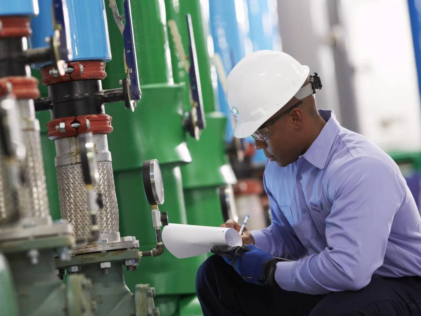 Technician in a hard hat recording HVAC equipment readings